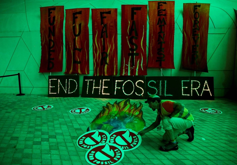 A climate activist arranges artwork expressing opposition to fossil fuels at Dubai's Expo City during the United Nations Climate Change Conference COP28 in Dubai on Dec. 12. A climate activist arranges artwork expressing opposition to fossil fuels at Dubai's Expo City during the United Nations Climate Change Conference COP28 in Dubai on Dec. 12.