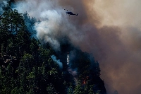 A helicopter waterbombs fires near Port Alberni, British Columbia, on June 6. Record wildfires devastated huge swaths of forest in Canada, with scientists saying the disasters were made worse by climate change. | Bloomberg