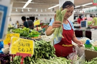 A vegetable vendor at a wet market in Beijing on Aug. 10. The Chinese economy was in focus throughout the year, with a lingering real estate downturn, a difficult geopolitical environment and a slow recovery from the COVID-19 pandemic all weighing on the world’s No. 2 economy. | Reuters