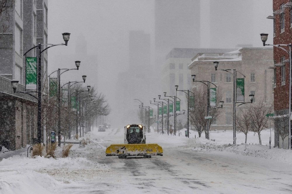 A snow plow drives down an empty street in Des Moines, Iowa, on Friday.  A snow plow drives down an empty street in Des Moines, Iowa, on Friday.