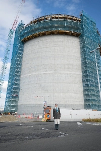 Conservation North’s Michelle Connolly stands in front of an under-construction storage tank at Sumitomo Corp.’s Sendai biomass power plant. | Mighty Earth