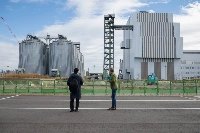 Ben Parfitt (right) stand outside Renova’s Sendai Gamo Biomass power plant. The round tanks on the left are for storing biomass fuel. | Mighty Earth