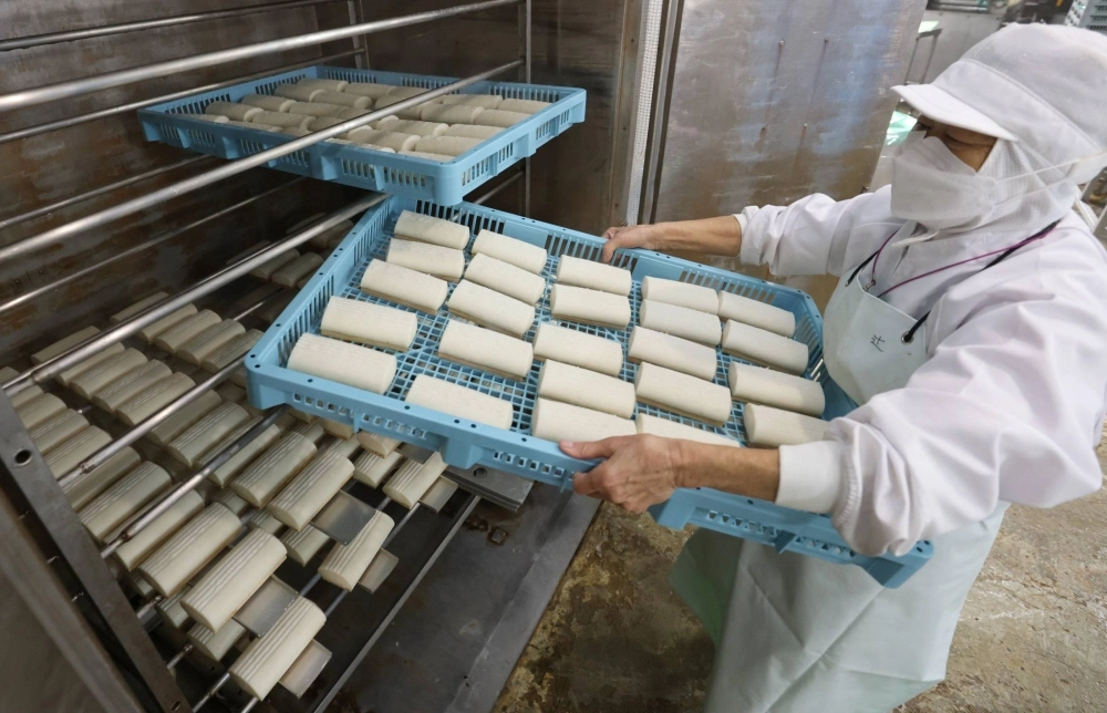 A worker carries a tray containing steamed kamaboko at a factory in Ise, Mie Prefecture. A worker carries a tray containing steamed kamaboko at a factory in Ise, Mie Prefecture.