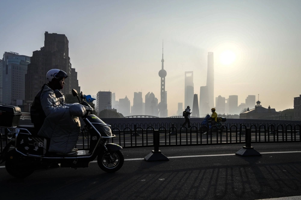 A man rides a scooter over a bridge across from the Lujiazui financial district in Shanghai on Jan. 9. A man rides a scooter over a bridge across from the Lujiazui financial district in Shanghai on Jan. 9.