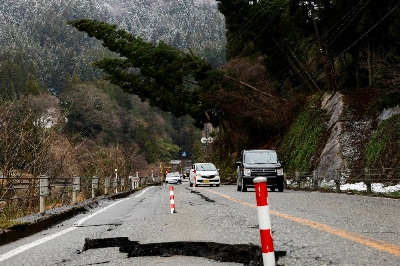Cars drive past a damaged road, in the aftermath of an earthquake, in Wajima, Ishikawa Prefecture. Cars drive past a damaged road, in the aftermath of an earthquake, in Wajima, Ishikawa Prefecture.