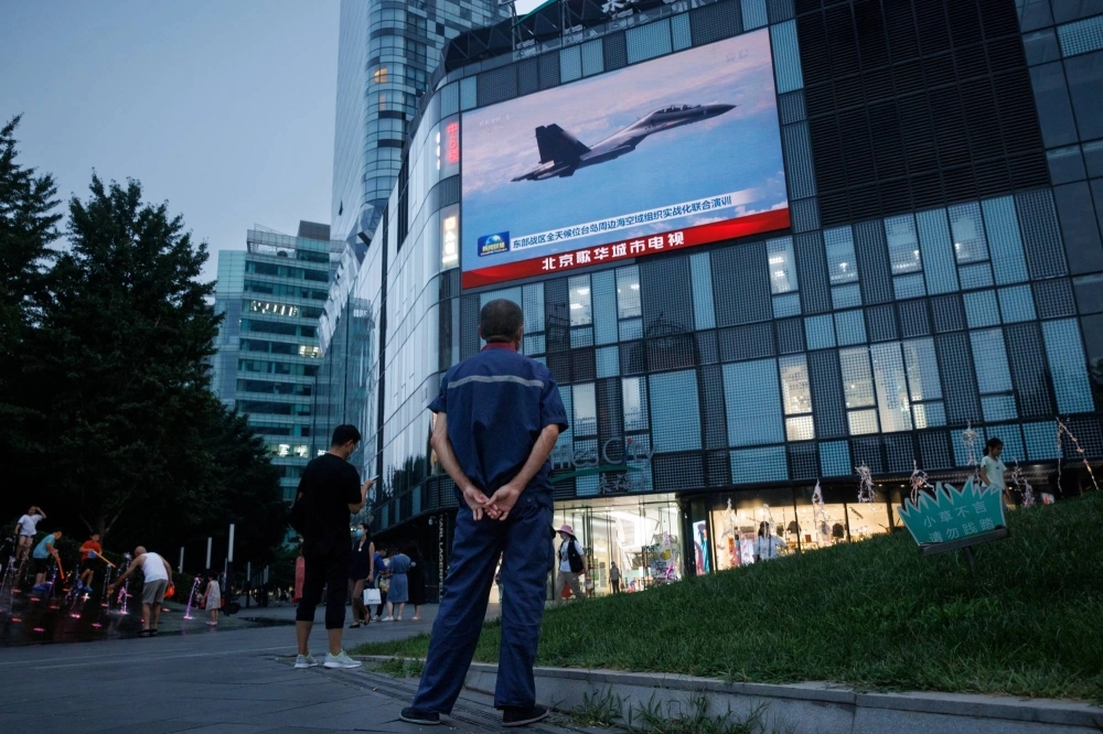 A man watches a news broadcast showing a fighter jet during joint military operations near Taiwan by the Chinese People's Liberation Army, at a shopping center in Beijing in August 2022.  A man watches a news broadcast showing a fighter jet during joint military operations near Taiwan by the Chinese People's Liberation Army, at a shopping center in Beijing in August 2022.