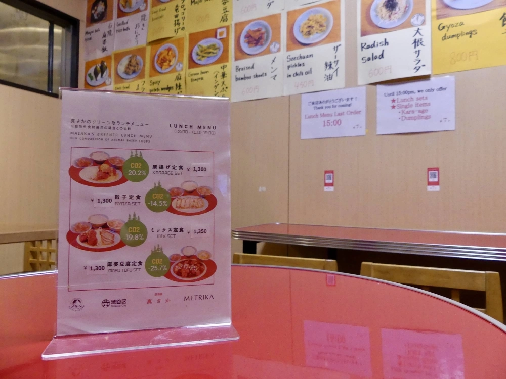 A menu at Masaka, a vegan restaurant in Tokyo’s Shibuya Ward, shows the rate of carbon dioxide emissions cuts for dishes compared with meat-based alternatives. A menu at Masaka, a vegan restaurant in Tokyo’s Shibuya Ward, shows the rate of carbon dioxide emissions cuts for dishes compared with meat-based alternatives.