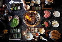 A woman grills a piece of beef at a barbeque restaurant in Yokohama. Greenhouse gas emissions from food amount to a third of all human-caused emissions. | REUTERS