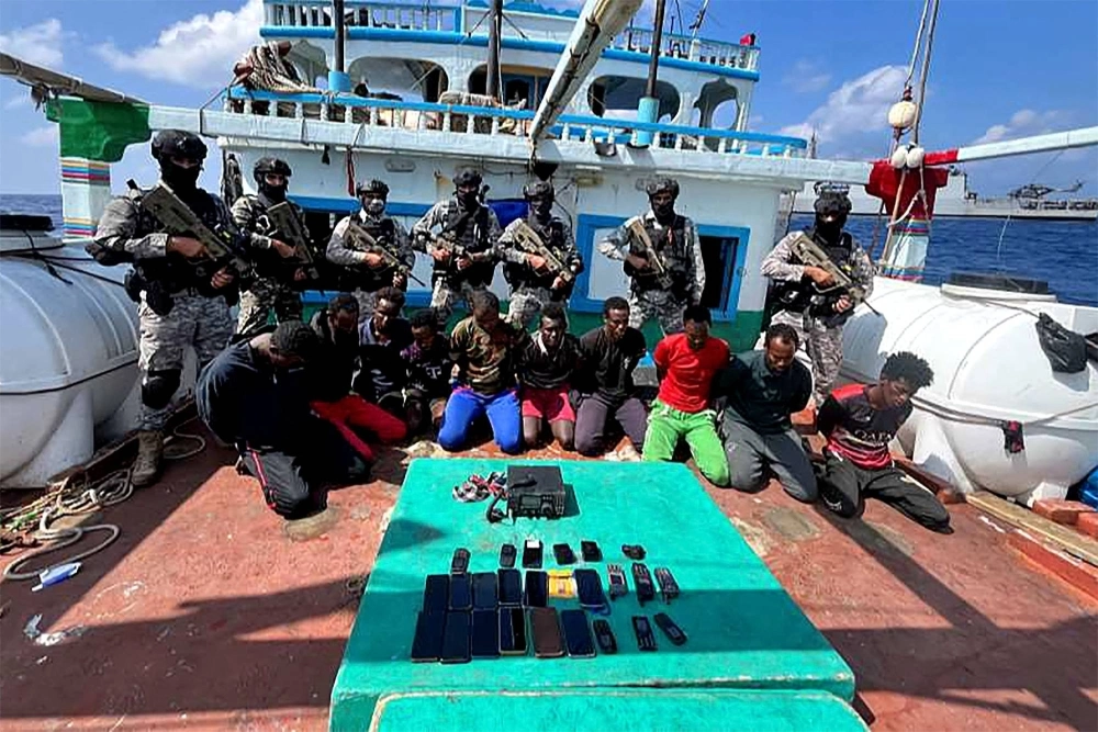 Indian commandos stand guard with a group of detained pirates after the Indian Navy freed an Iranian fishing vessel hijacked by Somali pirates on Tuesday.  Indian commandos stand guard with a group of detained pirates after the Indian Navy freed an Iranian fishing vessel hijacked by Somali pirates on Tuesday.