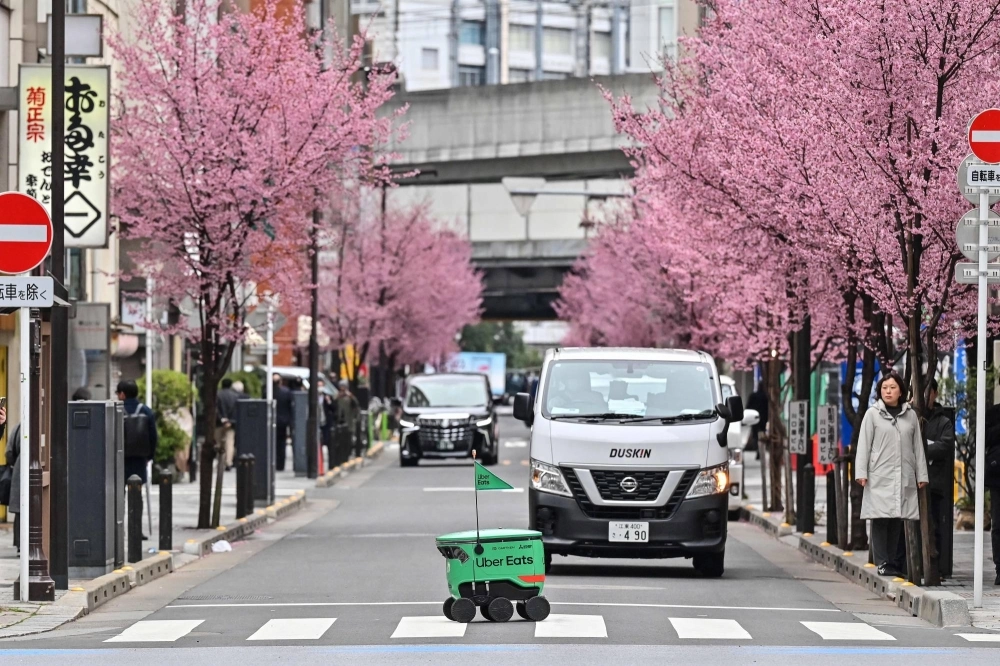 An unmanned robot navigates across a street during a demonstration of Uber Eats' robot delivery service in Tokyo on Tuesday. An unmanned robot navigates across a street during a demonstration of Uber Eats' robot delivery service in Tokyo on Tuesday.