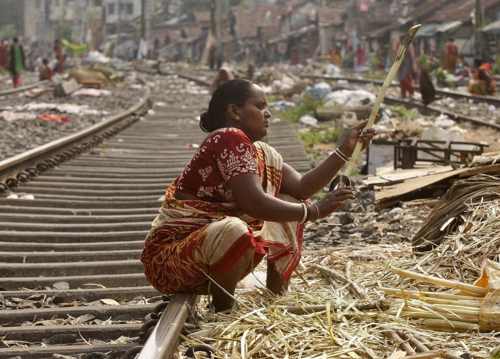A woman peels sugar cane on a railway track to sell it to sugar cane juice vendors in a slum area in Kolkata. A woman peels sugar cane on a railway track to sell it to sugar cane juice vendors in a slum area in Kolkata.