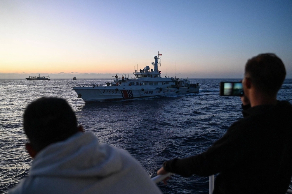 Philippine Coast Guard personnel film a China Coast Guard vessel during a supply mission in the disputed South China Sea on March 5. Philippine Coast Guard personnel film a China Coast Guard vessel during a supply mission in the disputed South China Sea on March 5.