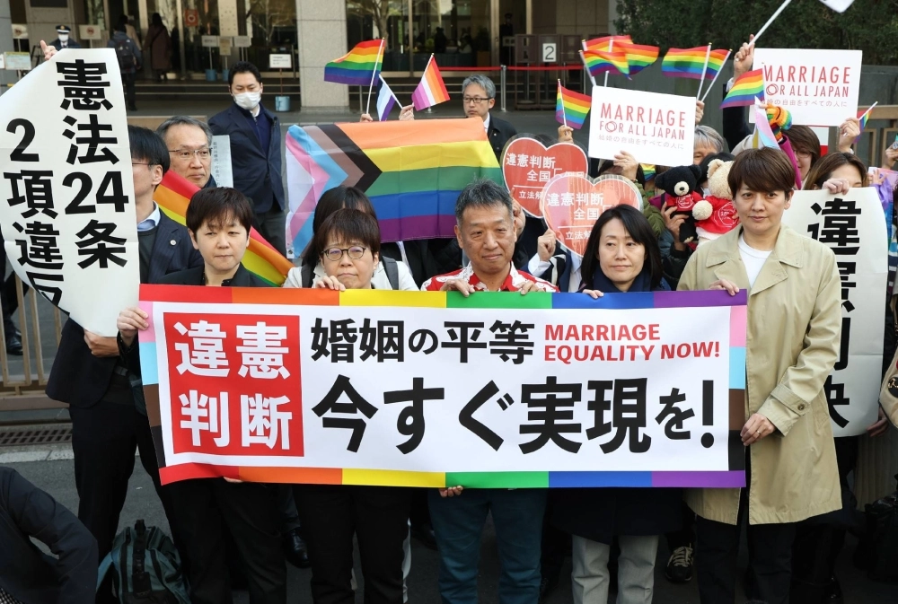 Plaintiffs of a lawsuit challenging the constitutionality of a ban on same-sex marriage and their supporters hold a banner calling for authorities to allow such unions in front of the Tokyo District Court on Thursday. Plaintiffs of a lawsuit challenging the constitutionality of a ban on same-sex marriage and their supporters hold a banner calling for authorities to allow such unions in front of the Tokyo District Court on Thursday.