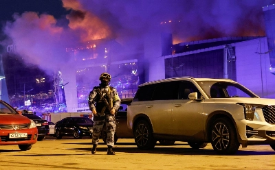A Russian law enforcement officer walks near the burning Crocus City Hall concert venue following a shooting incident, outside Moscow, on Friday. A Russian law enforcement officer walks near the burning Crocus City Hall concert venue following a shooting incident, outside Moscow, on Friday.