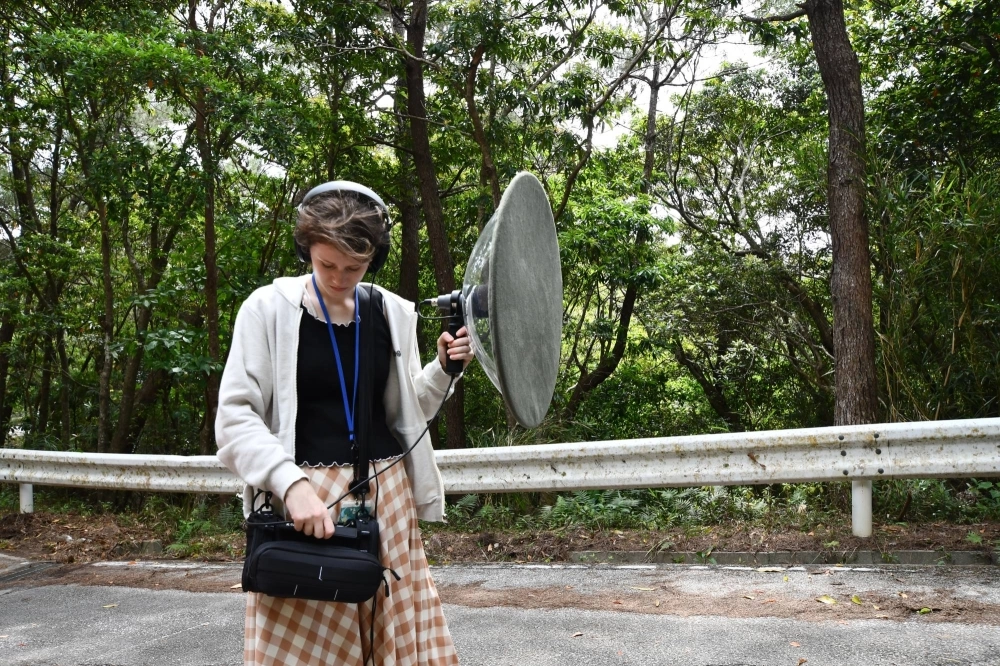 Cassondra George, a research assistant in the Environmental Science and Informatics Section at the Okinawa Institute of Science and Technology, listens to a recording of a bird call captured using a parabolic microphone in Onna, Okinawa Prefecture, on April 4. Parabolic microphones are sometimes used to identify specific bird calls. Cassondra George, a research assistant in the Environmental Science and Informatics Section at the Okinawa Institute of Science and Technology, listens to a recording of a bird call captured using a parabolic microphone in Onna, Okinawa Prefecture, on April 4. Parabolic microphones are sometimes used to identify specific bird calls.