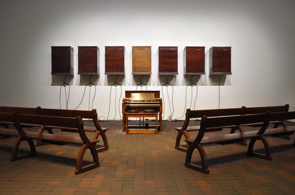 Theaster Gates' “A Heavenly Chord” lines up church pews before seven speakers and a Hammond B3 organ, a type of electric organ prevalent in Black American churches. Theaster Gates' “A Heavenly Chord” lines up church pews before seven speakers and a Hammond B3 organ, a type of electric organ prevalent in Black American churches.