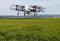 An automated drone flies over rice plants, spraying pesticide while diagnosing growth of individual rice stalks, during a demonstration in Tome, Miyagi Prefecture, in 2018. Although the price of rice monitoring technology might be too steep for family-run farms, the national government provides funds to support such efforts. | Reuters