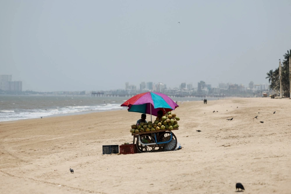 A vendor selling coconut water waits for customers at a beach on a hot day in Mumbai, India, on Monday.  A vendor selling coconut water waits for customers at a beach on a hot day in Mumbai, India, on Monday.