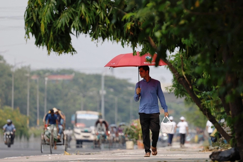 A man walks along a road with an umbrella to cover himself from the sun during a countrywide heat wave in Dhaka, Bangladesh, on Sunday. A man walks along a road with an umbrella to cover himself from the sun during a countrywide heat wave in Dhaka, Bangladesh, on Sunday.