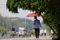 A man walks along a road with an umbrella to cover himself from the sun during a countrywide heat wave in Dhaka, Bangladesh, on Sunday. | REUTERS
