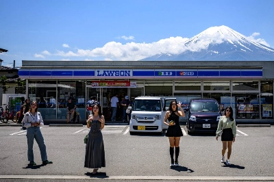 Tourists pose in front of a convenience store with Mount Fuji on Friday in the town of Fujikawaguchiko, Yamanashi Prefecture. Local residents are upset over littering, overcrowding and the inconvenience caused by the visitors. Tourists pose in front of a convenience store with Mount Fuji on Friday in the town of Fujikawaguchiko, Yamanashi Prefecture. Local residents are upset over littering, overcrowding and the inconvenience caused by the visitors.