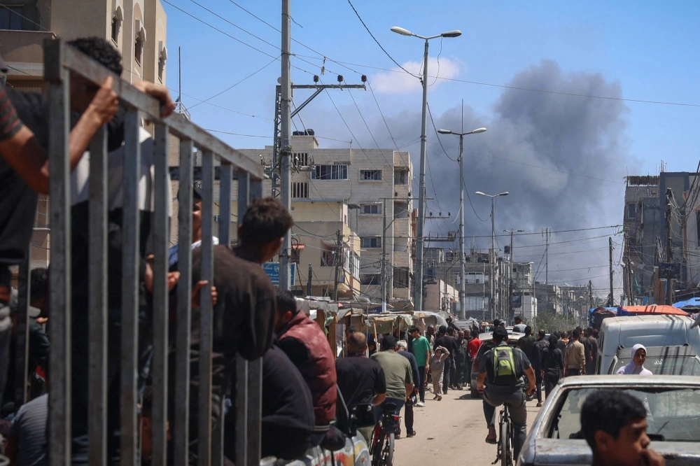 Palestinians crowd a street as smoke billows after Israeli strikes in Rafah on Tuesday. Palestinians crowd a street as smoke billows after Israeli strikes in Rafah on Tuesday.
