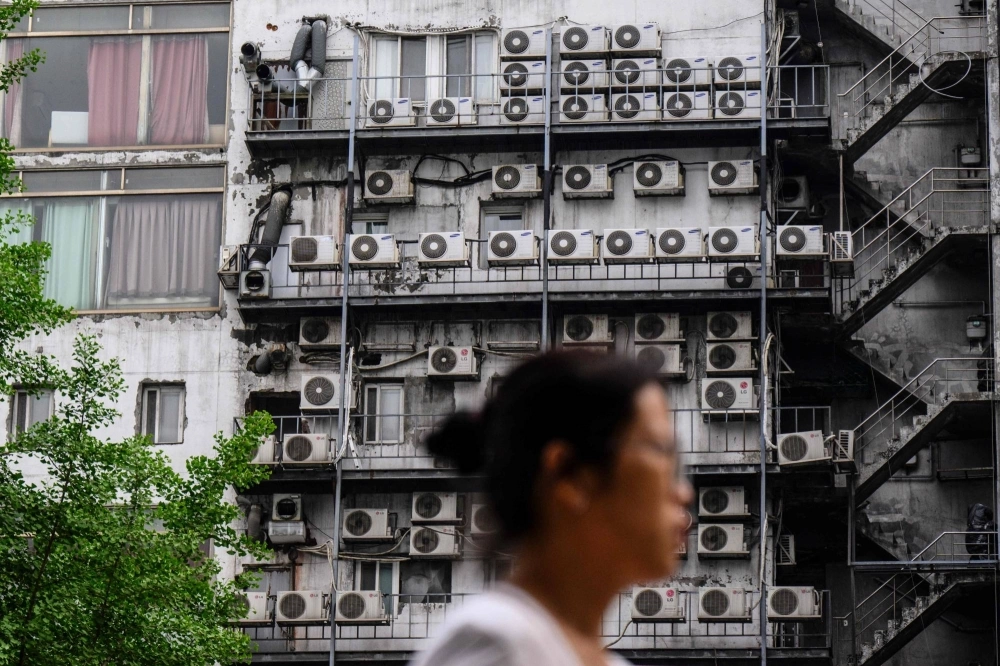 A woman walks past air-conditioning units on a building in Seoul on April 30. A woman walks past air-conditioning units on a building in Seoul on April 30.
