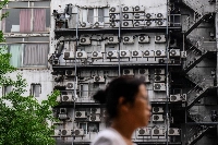 A woman walks past air-conditioning units on a building in Seoul on April 30. | AFP-JIJI