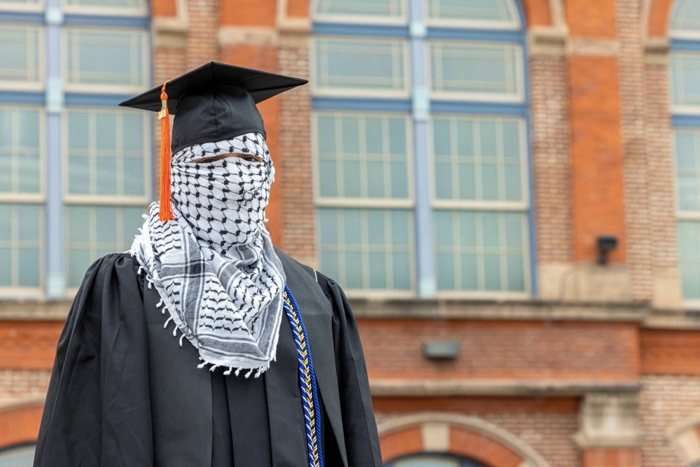A Palestinian student, who plans to return to his homeland after graduation and who wishes to remain anonymous, poses for a portrait while wearing a kaffiyeh along with his commencement cap at the Auraria Campus in Denver on Friday. A Palestinian student, who plans to return to his homeland after graduation and who wishes to remain anonymous, poses for a portrait while wearing a kaffiyeh along with his commencement cap at the Auraria Campus in Denver on Friday.