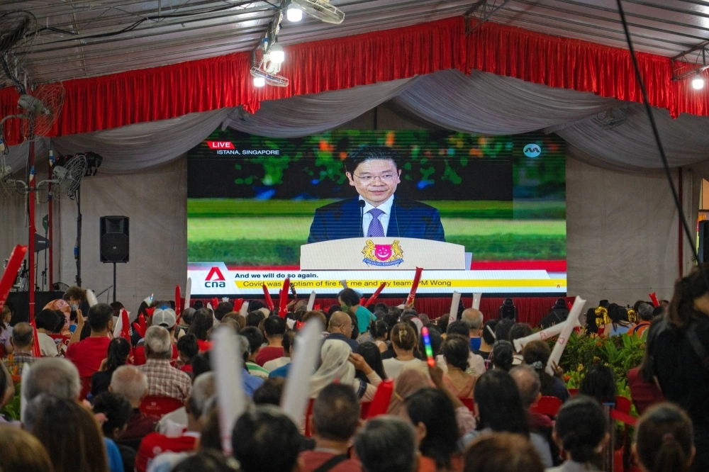 Attendees watch a broadcast of the swearing-in ceremony of Singapore’s Prime Minister Lawrence Wong on Wednesday. Attendees watch a broadcast of the swearing-in ceremony of Singapore’s Prime Minister Lawrence Wong on Wednesday.