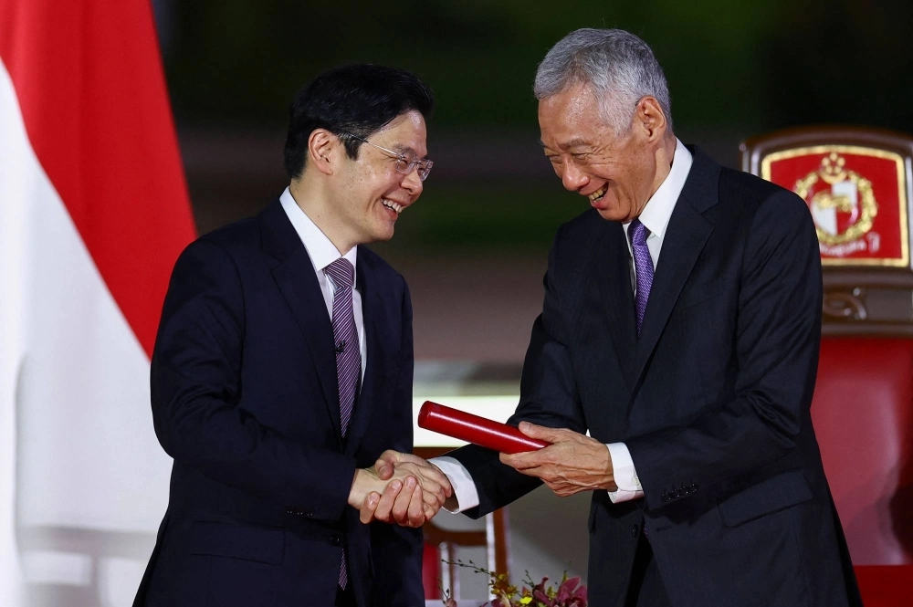 Singapore's new prime minister, Lawrence Wong (left), shakes hands with his predecessor, Lee Hsien Loong, during the swearing-in ceremony at the Istana in Singapore on Wednesday. Singapore's new prime minister, Lawrence Wong (left), shakes hands with his predecessor, Lee Hsien Loong, during the swearing-in ceremony at the Istana in Singapore on Wednesday.