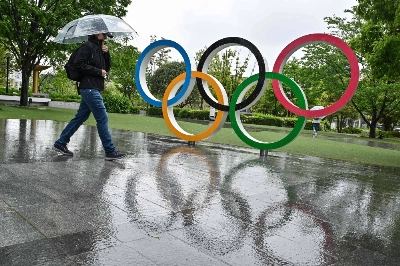 A visitor to the Japan Olympic Museum walks past a display of the Olympic Rings on a wet day in central Tokyo on May 1. A visitor to the Japan Olympic Museum walks past a display of the Olympic Rings on a wet day in central Tokyo on May 1.
