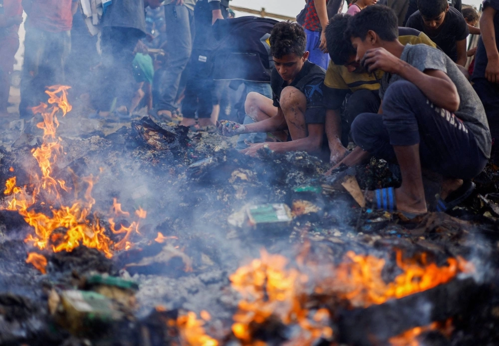 Palestinians search for food among burnt debris in the aftermath of an Israeli strike on an area designated for displaced people, in Rafah in the southern Gaza Strip, on Monday. Palestinians search for food among burnt debris in the aftermath of an Israeli strike on an area designated for displaced people, in Rafah in the southern Gaza Strip, on Monday.