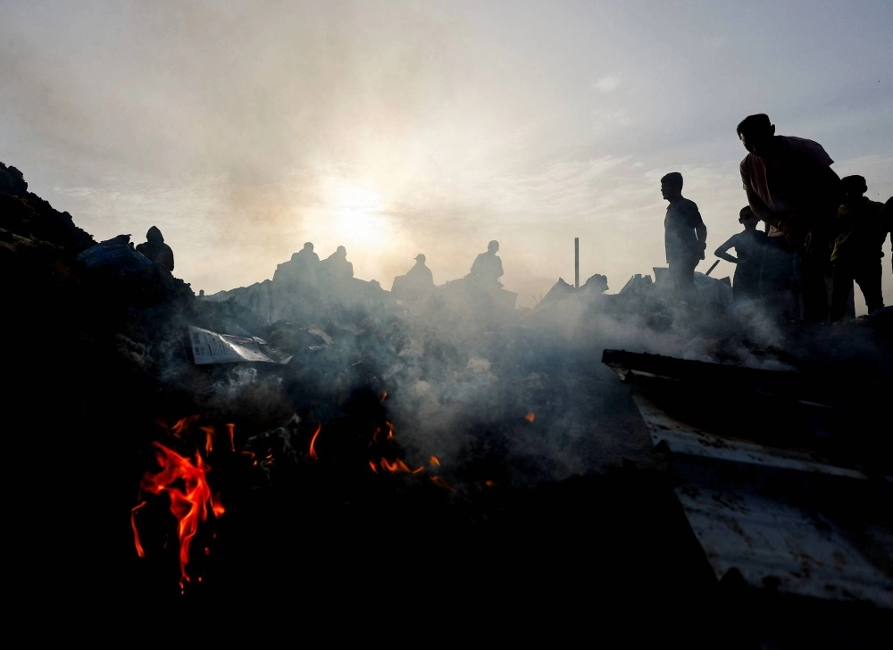 Palestinians search for food among burnt debris in the aftermath of an Israeli strike on an area designated for displaced people, in Rafah in the southern Gaza Strip, on Sunday. Palestinians search for food among burnt debris in the aftermath of an Israeli strike on an area designated for displaced people, in Rafah in the southern Gaza Strip, on Sunday.