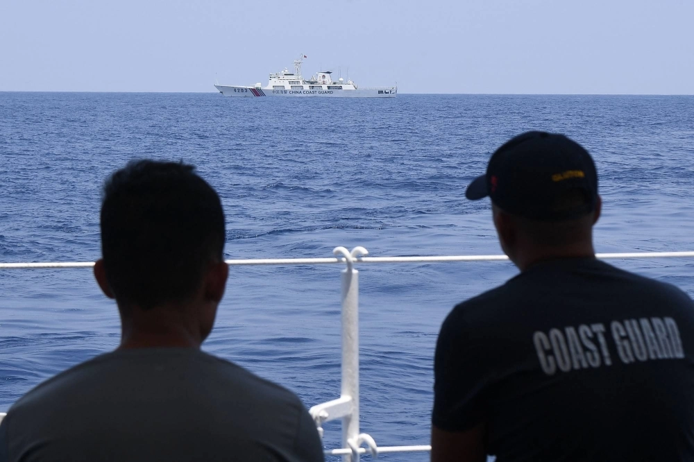 Philippine Coast Guard personnel aboard the BRP Bagacay observe a China Coast Guard ship during the distribution of fuel and food to fishers by a civilian-led mission in the disputed South China Sea on May 16. Philippine Coast Guard personnel aboard the BRP Bagacay observe a China Coast Guard ship during the distribution of fuel and food to fishers by a civilian-led mission in the disputed South China Sea on May 16.