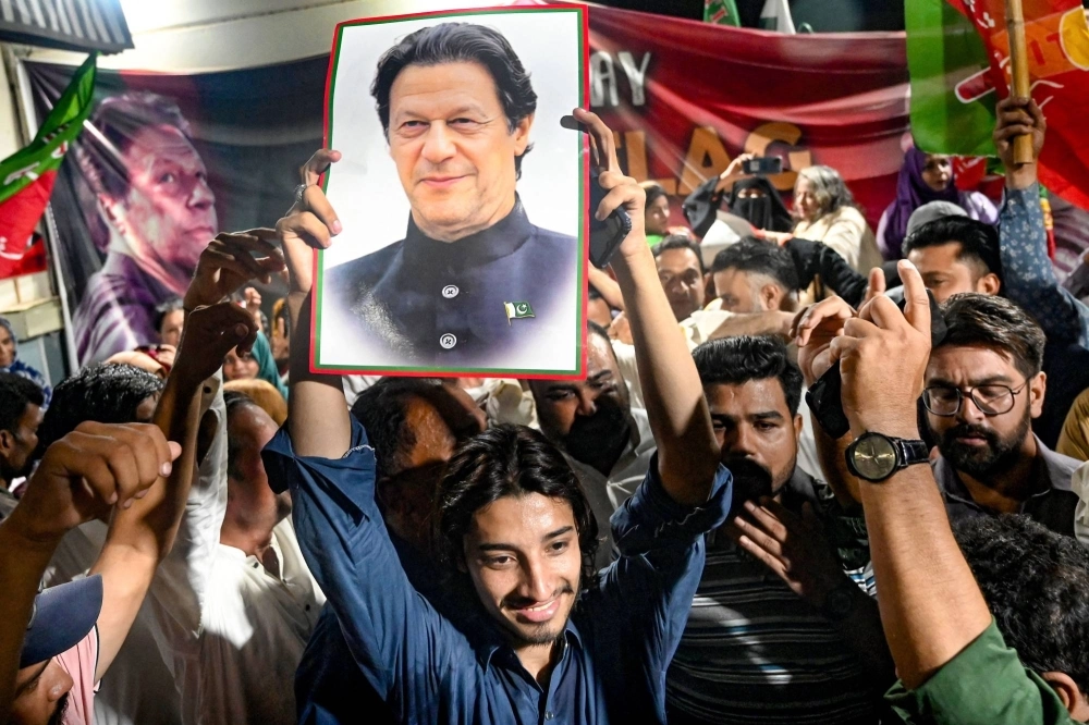 Supporters of Pakistan's jailed former Prime Minister Imran Khan in Karachi hold his poster as they celebrate his acquittal of leaking state secrets following a court verdict on Monday. Supporters of Pakistan's jailed former Prime Minister Imran Khan in Karachi hold his poster as they celebrate his acquittal of leaking state secrets following a court verdict on Monday.