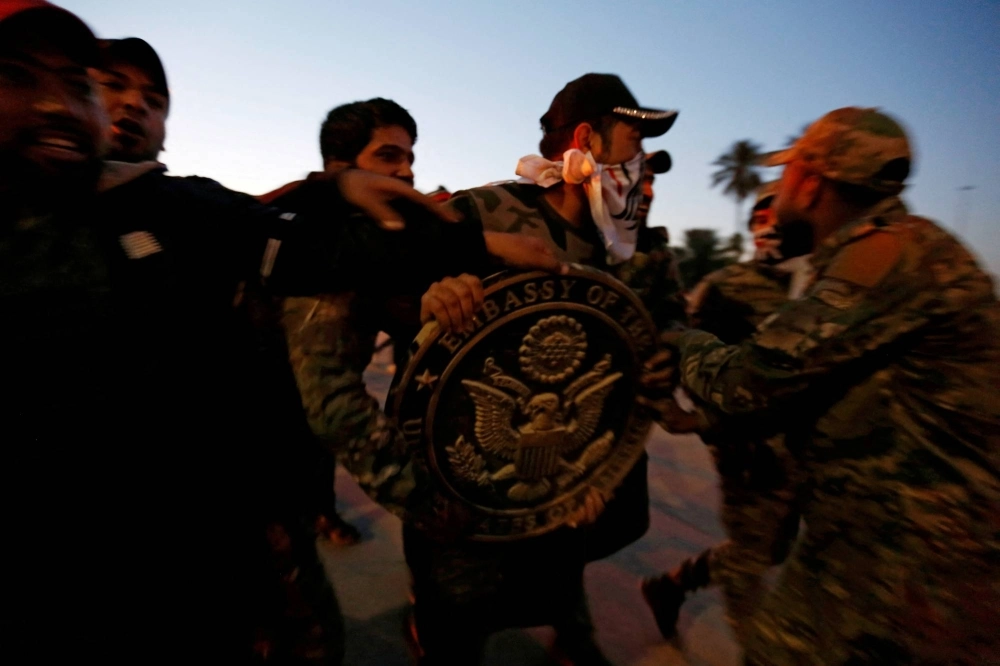 Protesters and militia fighters carry the logo of the U.S. Embassy during a protest to condemn airstrikes on bases belonging to Hashd al-Shaabi (paramilitary forces), in Baghdad on Dec. 31, 2019. Protesters and militia fighters carry the logo of the U.S. Embassy during a protest to condemn airstrikes on bases belonging to Hashd al-Shaabi (paramilitary forces), in Baghdad on Dec. 31, 2019.