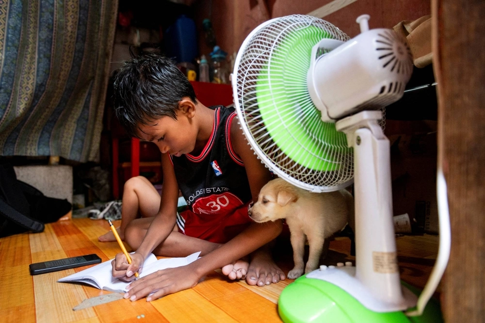 A student answers his learning module following the suspension of in-person classes, inside his house in Manila on April 26. A student answers his learning module following the suspension of in-person classes, inside his house in Manila on April 26.