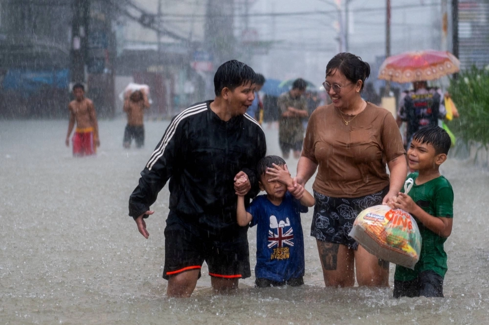People wade through a flooded road in Balagtas, Bulacan province, Philippines, on July 29, 2023.  People wade through a flooded road in Balagtas, Bulacan province, Philippines, on July 29, 2023.