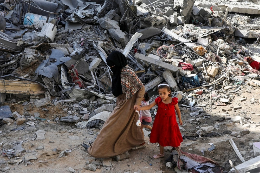 A woman and child walk among debris in Nuseirat refugee camp in the central Gaza Strip on Sunday.  A woman and child walk among debris in Nuseirat refugee camp in the central Gaza Strip on Sunday.