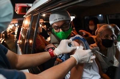 A health worker puts on an adhesive bandage after inoculating a man with a booster shot of the Sinovac COVID-19 vaccine in Manila in January 2022.  A health worker puts on an adhesive bandage after inoculating a man with a booster shot of the Sinovac COVID-19 vaccine in Manila in January 2022.