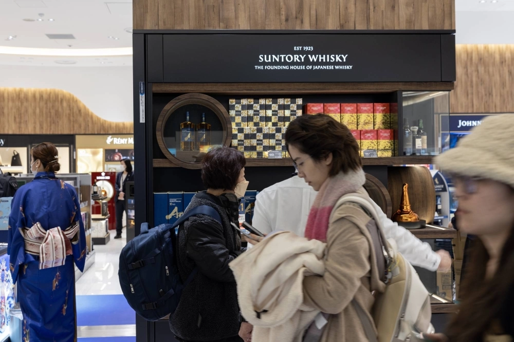 Travelers in front of a Suntory duty-free shop at Kansai International Airport in December Travelers in front of a Suntory duty-free shop at Kansai International Airport in December