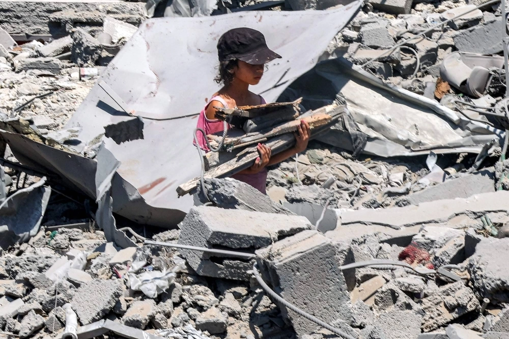 A girl walks with salvaged wood through rubble at the site of a building that was hit by Israeli bombardment in the Sabra neighborhood in the south of Gaza City on Thursday. A girl walks with salvaged wood through rubble at the site of a building that was hit by Israeli bombardment in the Sabra neighborhood in the south of Gaza City on Thursday.