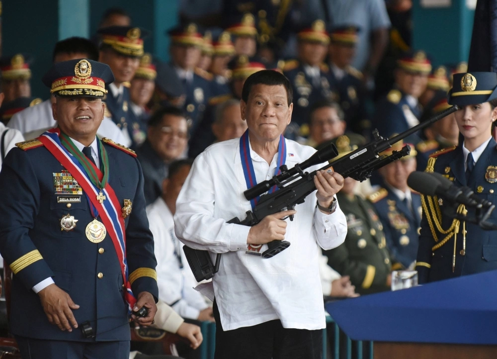 Then-Philippine President Rodrigo Duterte holds a sniper rifle next to outgoing Philippine National Police Chief Ronald Bato Dela Rosa during the National Police chief handover ceremony in Camp Crame, Quezon City, in metro Manila, in April 2018. Then-Philippine President Rodrigo Duterte holds a sniper rifle next to outgoing Philippine National Police Chief Ronald Bato Dela Rosa during the National Police chief handover ceremony in Camp Crame, Quezon City, in metro Manila, in April 2018.