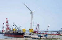 A floating wind turbine for an experimental offshore power generation project is unveiled at Onahama port in Iwaki, Fukushima Prefecture, in June 2015. | Jiji