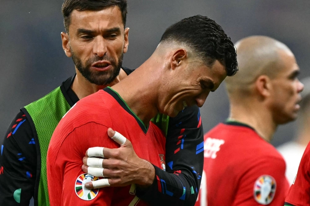 Portugal forward Cristiano Ronaldo (center) is comforted by goalkeeper Rui Patricio after failing to score a penalty during a UEFA Euro 2024 clash against Slovenia in Frankfurt on Monday. Portugal forward Cristiano Ronaldo (center) is comforted by goalkeeper Rui Patricio after failing to score a penalty during a UEFA Euro 2024 clash against Slovenia in Frankfurt on Monday.
