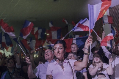 Supporters of the far-right National Rally wave French flags at the party's headquarters following voting during the first round of legislative elections in Henin-Beaumont, France, on Sunday. Supporters of the far-right National Rally wave French flags at the party's headquarters following voting during the first round of legislative elections in Henin-Beaumont, France, on Sunday.