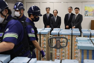 Bank of Japan Gov. Kazuo Ueda (back center) watches as workers prepare to ship the first bundles of newly designed ¥10,000 bills at the central bank's headquarters in Tokyo on Wednesday. Bank of Japan Gov. Kazuo Ueda (back center) watches as workers prepare to ship the first bundles of newly designed ¥10,000 bills at the central bank's headquarters in Tokyo on Wednesday.