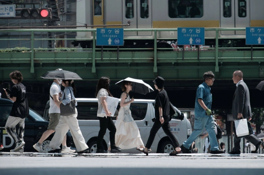 Pedestrians shelter themselves from the sun using parasols as they cross a street in the Shinjuku district of Tokyo on Thursday. The temperature in Tokyo hit 35 degrees Celsius just after noon on Thursday, the first time so far this year. Pedestrians shelter themselves from the sun using parasols as they cross a street in the Shinjuku district of Tokyo on Thursday. The temperature in Tokyo hit 35 degrees Celsius just after noon on Thursday, the first time so far this year.