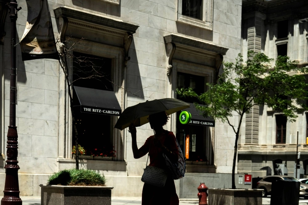 A pedestrian uses an umbrella for shade during high temperatures in Philadelphia. A pedestrian uses an umbrella for shade during high temperatures in Philadelphia.